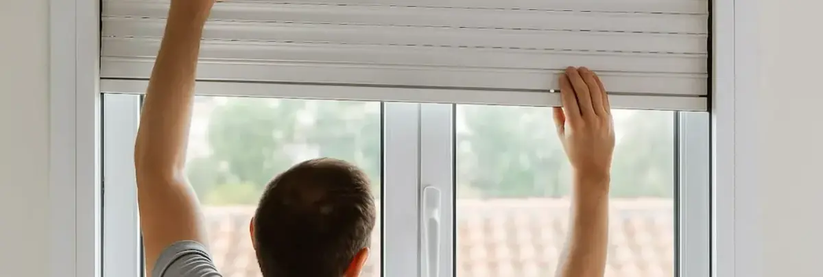 Homme levant à la main un volet roulant intérieur resté bloqué
